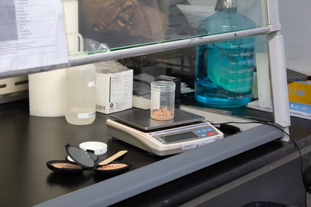 Cosmetic products on a digital scale in preparation for testing in a cosmetic testing laboratory.