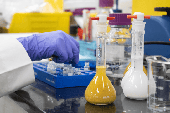 Scientists examining vial of cosmetics in laboratory. 