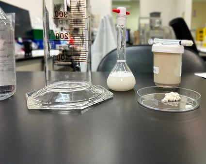 Graduated cylinder, flask, and petri dish filled with an over-the-counter cream for laboratory testing.  
