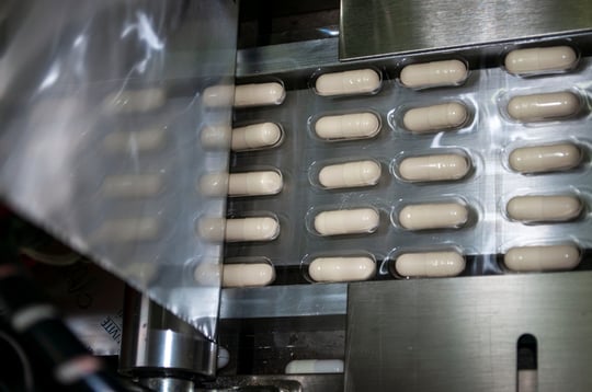 Dietary supplement capsules in packaging on assembly line.  