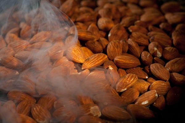 Steam rising from a tray of roasted almonds. 