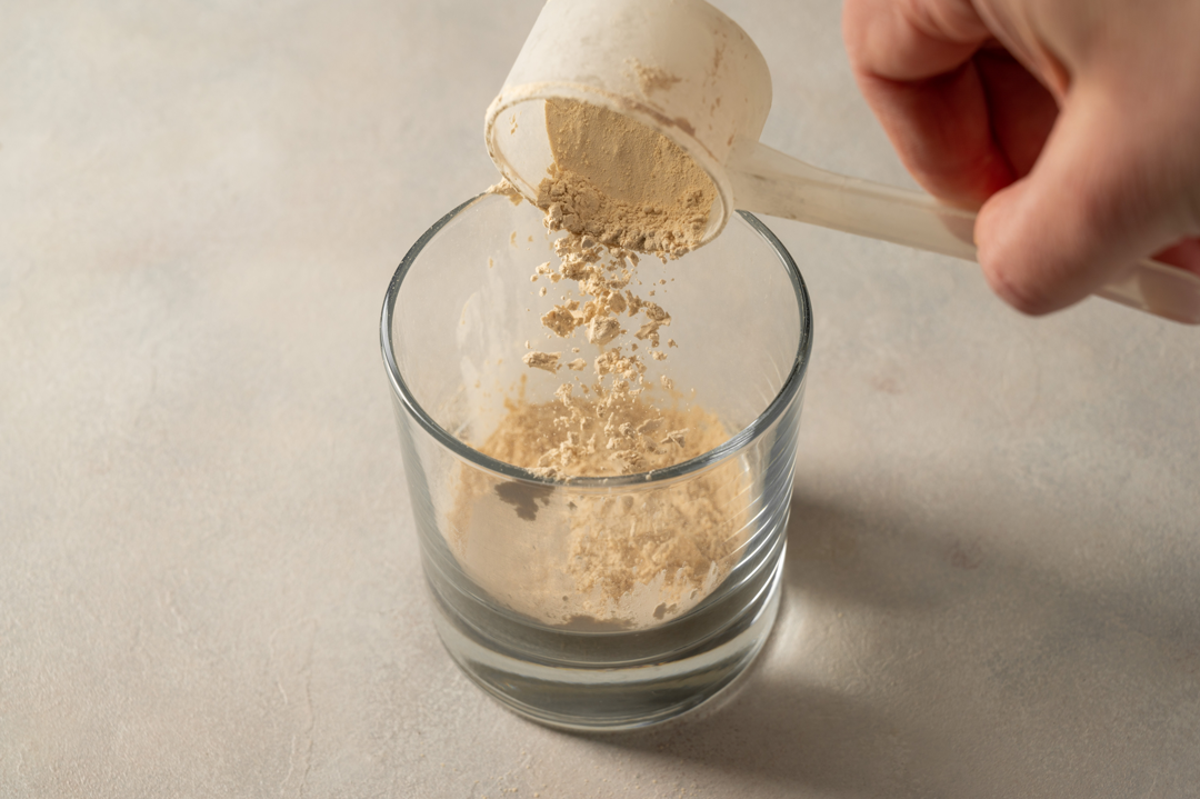 Person pouring protein powder into a glass. 